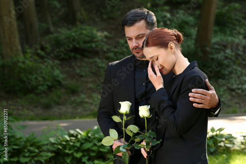 Funeral ceremony. Man comforting woman outdoors, space for text