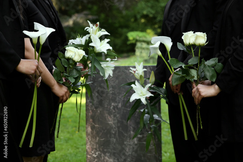 Cuadro en lienzo People with flowers near granite tombstone at cemetery outdoors, closeup