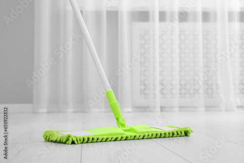 Cleaning dirty wooden floor with mop indoors