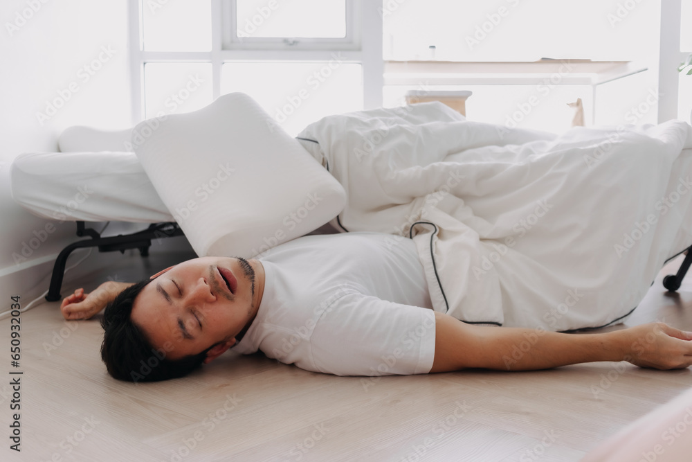 Asian man lying on floor snoring fall from white bed at home. Asian man lying on floor snoring fall from white bed at home.