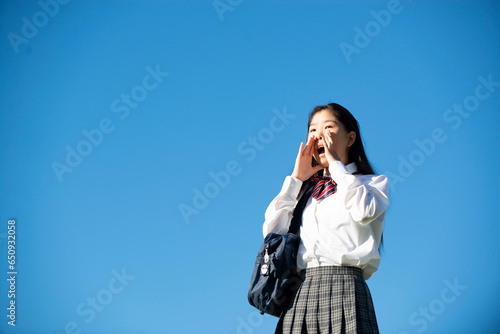 口元に手を当てて叫んでいる制服姿の女子学生 photo