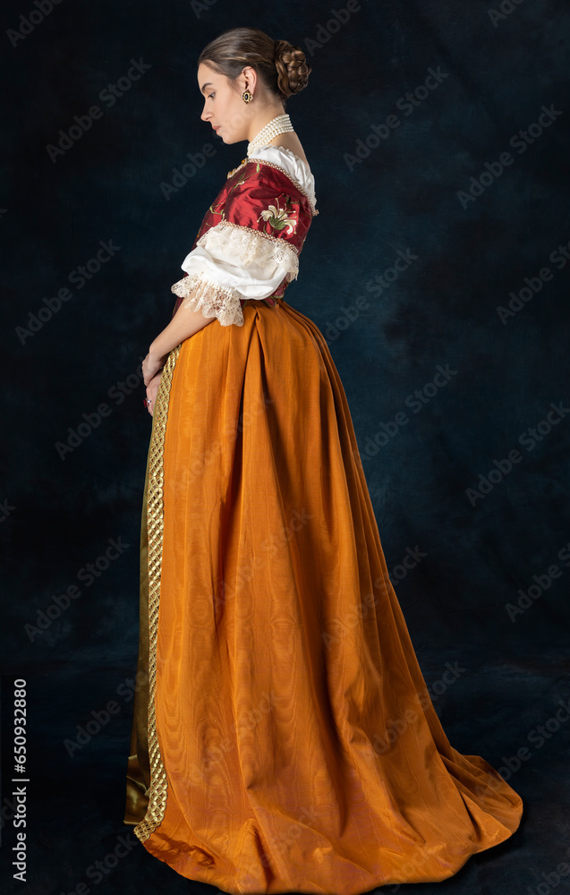 Woman wearing a Renaissance, Tudor, Georgian, or high fantasy costume with a red embroidered bodice and a pearl choker Woman wearing a Renaissance, Tudor, Georgian, or high fantasy costume with a red embroidered bodice and a pearl choker