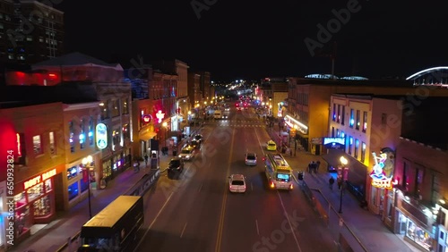 Aerial Forward Shot Of Vehicles And People On Street Amidst Illuminated Buildings In City At Night - Nashville, Tennessee