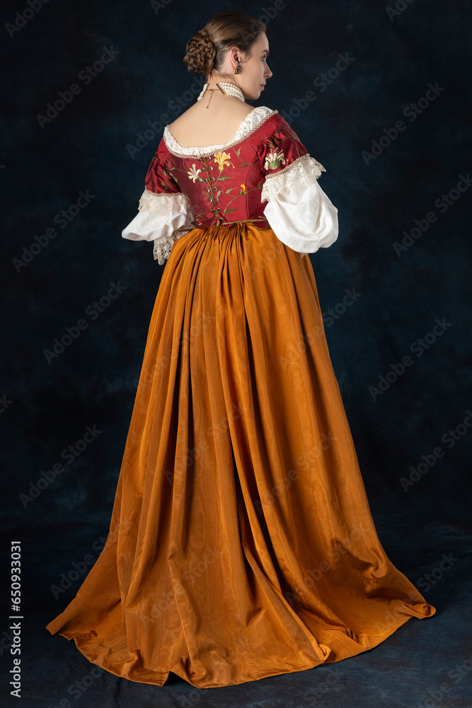 Woman wearing a Renaissance, Tudor, Georgian, or high fantasy costume with a red embroidered bodice and a pearl choker Woman wearing a Renaissance, Tudor, Georgian, or high fantasy costume with a red embroidered bodice and a pearl choker