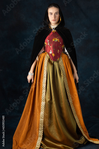Woman in a renaissance, Tudor, Georgian, or high fantasy costume with a red embroidered bodice and a silk velvet cloak