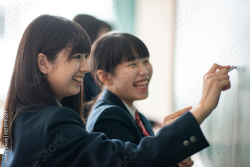 チョークで黒板に答えを書く女子学生