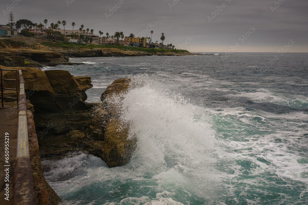 2023-09-15 WAVES CRASHING ON THE ROCKS BY THE CHILDRENS POOL ALONG THE SHORELINE OF LA JOLLA WITH A CLOUDY SKY