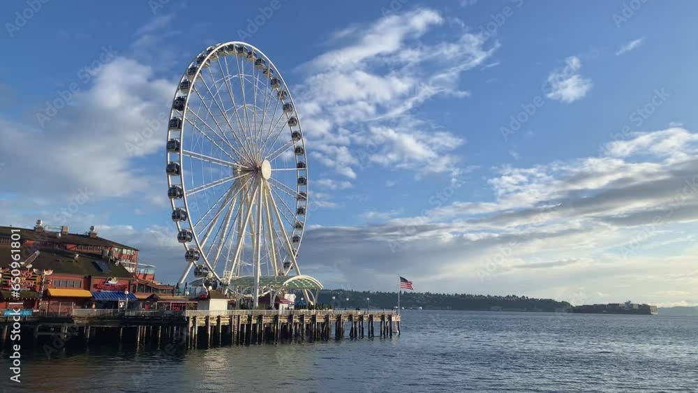 Beautiful wide shot of the famous Seattle tourist destination ferris wheel on pier 57 during golden hour on a warm sunny summer day in the state of Washington in the United States of America Beautiful wide shot of the famous Seattle tourist destination ferris wheel on pier 57 during golden hour on a warm sunny summer day in the state of Washington in the United States of America