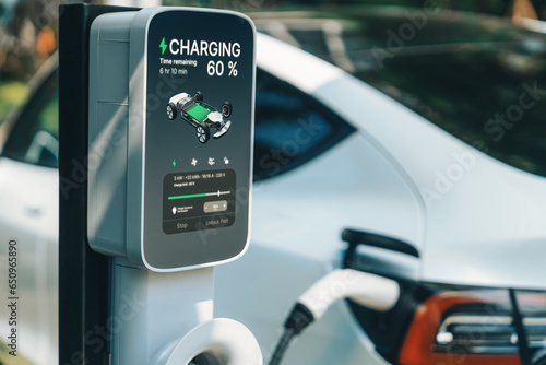 EV electric car charging in green sustainable city outdoor garden in summer. Urban sustainability lifestyle by green clean rechargeable energy of electric BEV vehicle innards