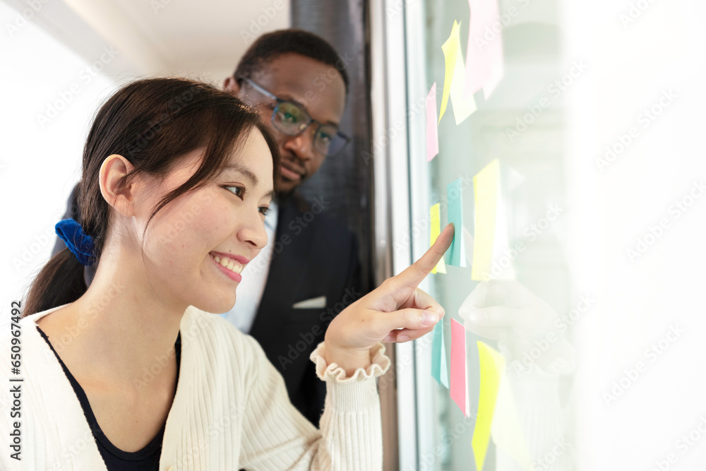 Happy multiethnic business team meeting pointing at post it notes on ...