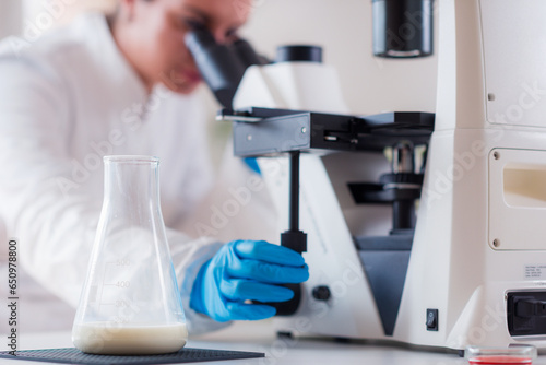 A quality control specialist inspects milk samples under a microscope in a lab