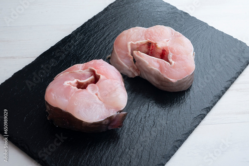 Slices of fresh conger eel on a black board.