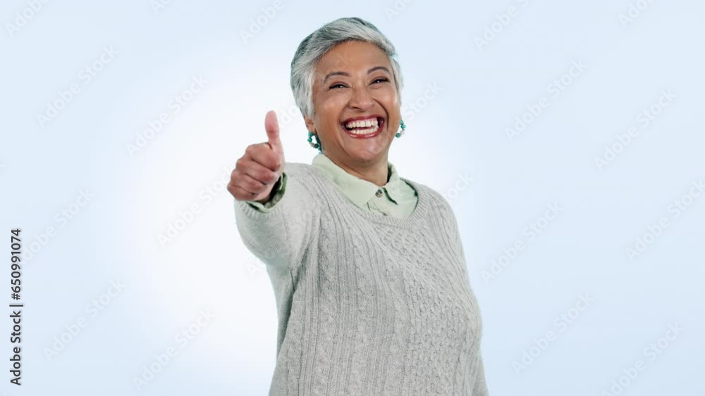 Face, smile and senior woman with thumbs up, agreement and promotion on blue studio background. Portrait, mature person or happy model with hand gesture, icon and feedback with review, emoji and like Face, smile and senior woman with thumbs up, agreement and promotion on blue studio background. Portrait, mature person or happy model with hand gesture, icon and feedback with review, emoji and like