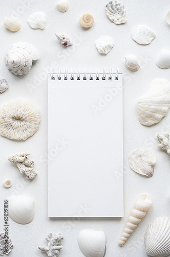 Blank notebook surrounded sea shells. Summer memories concepts.