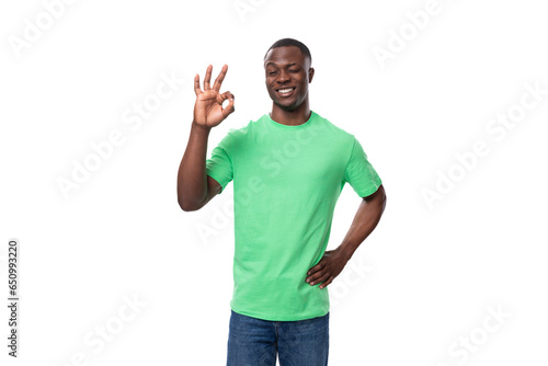 young handsome happy african man in light green t-shirt and jeans on white background