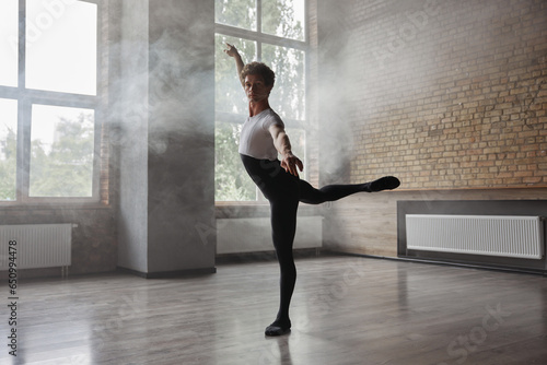 Fototapeta Naklejka Na Ścianę i Meble -  Confidence male ballet dancer practicing alone in studio room