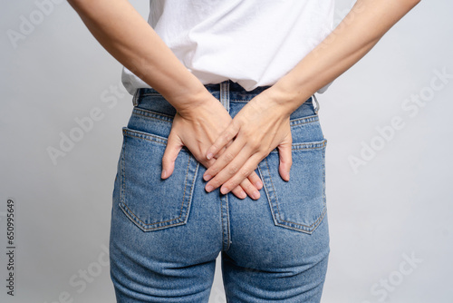 Asian woman uses hands to touch her butt with hemorrhoids health care concept