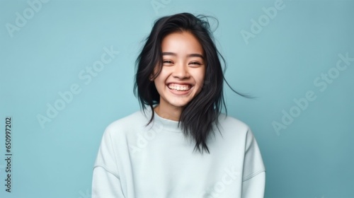 A bubbly and lively young girl grinning from ear to ear against a gently lit studio backdrop.