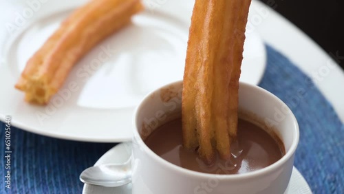 A slow-motion footage dipping Spanish churros in hot chocolate sauce.