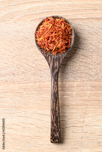 Dried safflower in spoon on wooden background, Herbal tea