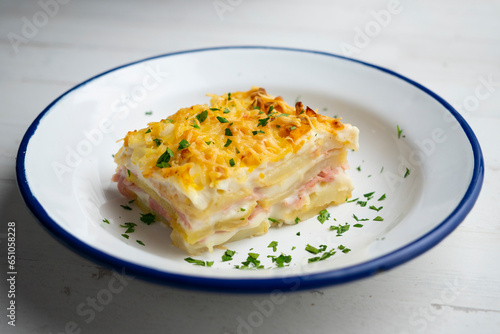 Foto Potato and bechamel lasagna. Recipe with ham and grilled cheese.