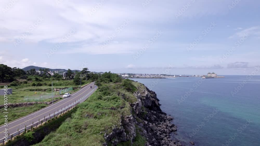 Drone video of coastal cliff road in Jeju Island, South Korea with white clouds and blue sky Drone video of coastal cliff road in Jeju Island, South Korea with white clouds and blue sky