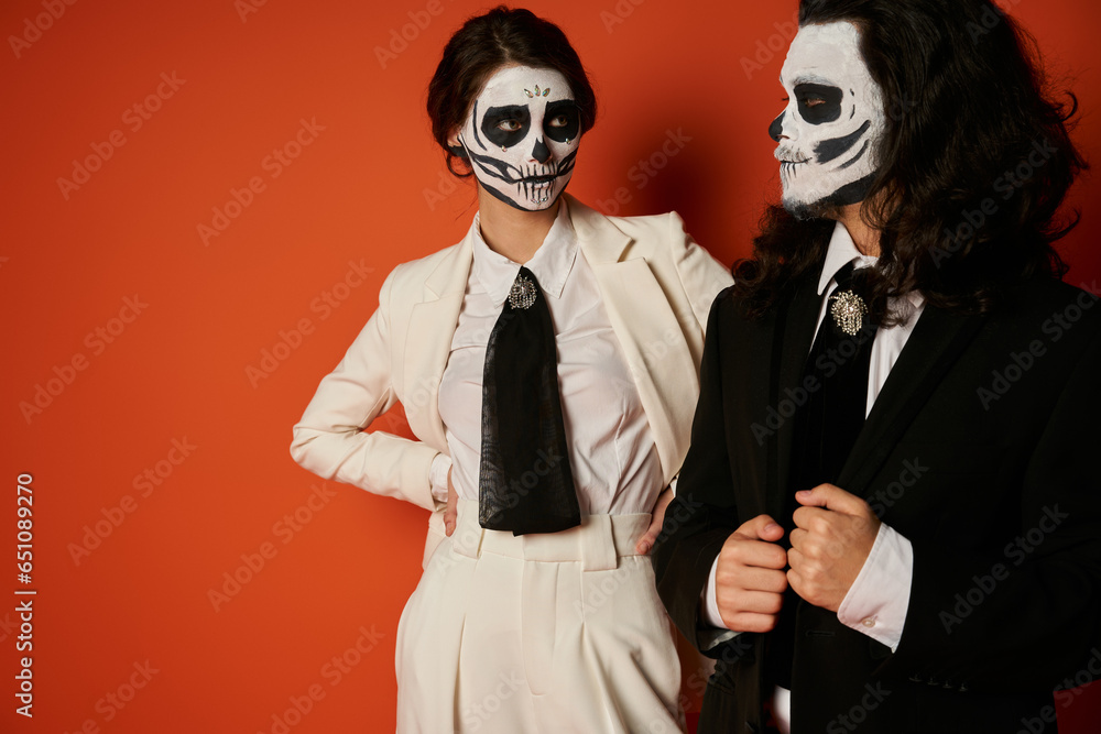 woman in skeleton makeup and white suit looking at spooky man on red, dia de lost muertos tradition woman in skeleton makeup and white suit looking at spooky man on red, dia de lost muertos tradition