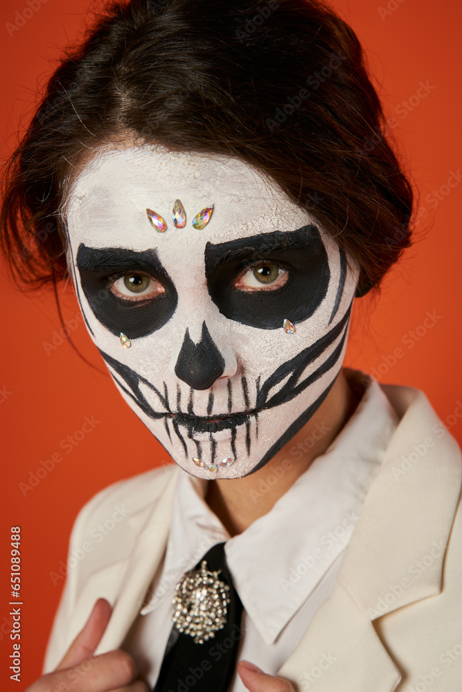 portrait of woman in scary sugar skull makeup looking at camera on red, dia de los muertos tradition portrait of woman in scary sugar skull makeup looking at camera on red, dia de los muertos tradition