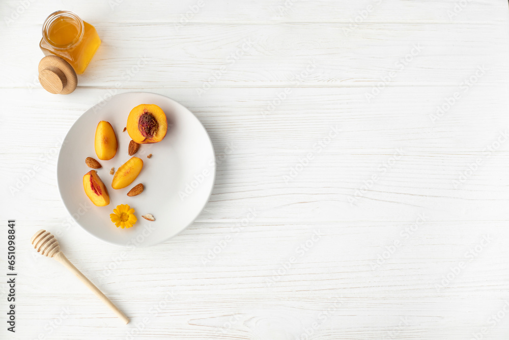 A plate with an apricot, honey and a honey spoon on a white background A plate with an apricot, honey and a honey spoon on a white background