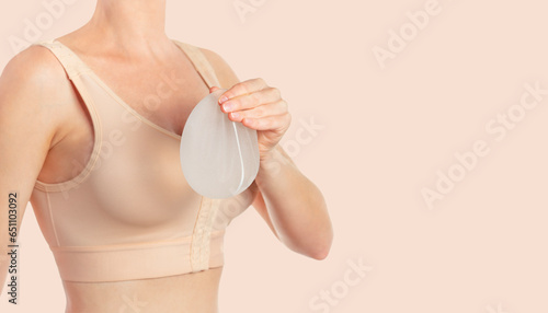 Woman wearing compressing bra after breast augmentation. Holding implants photo