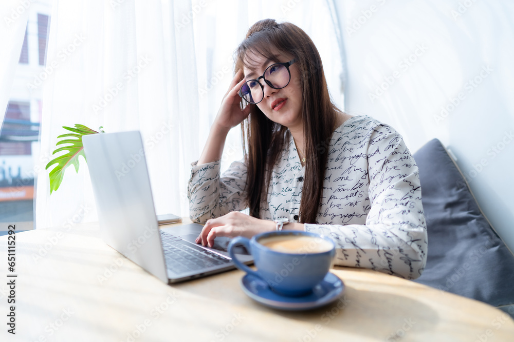 Stressed freelance people business asian female Having Headache While Working Using laptop computer with coffee cup and smartphone at window in coffee shop like the background Stressed freelance people business asian female Having Headache While Working Using laptop computer with coffee cup and smartphone at window in coffee shop like the background