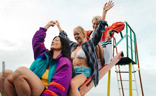 Fun with friends: Three women sliding down a slide at a play park photo