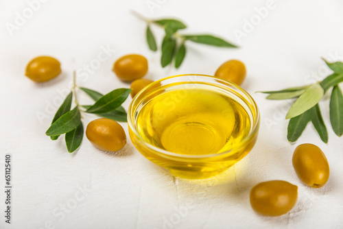 Olive oil in glass bowls, gravy boats and bottle on a textured kitchen table. Oil bottle with branches and fruits of olives. Place for text. copy space. cooking oil and salad dressing.Close-up.Flatley