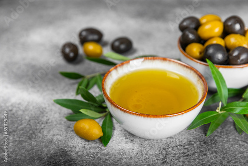 Olive oil in glass bowls, gravy boats and bottle on a textured kitchen table. Oil bottle with branches and fruits of olives. Place for text. copy space. cooking oil and salad dressing.Close-up.Flatley