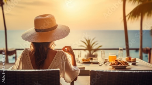Young woman on summer vacation enjoying breakfast on a luxury hotel resort terrace overlooking the sea. © Oulaphone