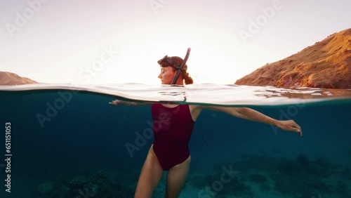 Portrait of the woman freediver swimming in the sea at sunset. Young woman in pink suit relaxes in the water and enjoys swimming in the tropical sea in Indonesia at sunset photo