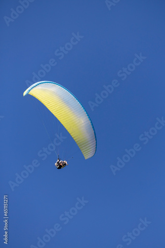 Tandem paragliding over blue sky. Yellow, white and blue color
