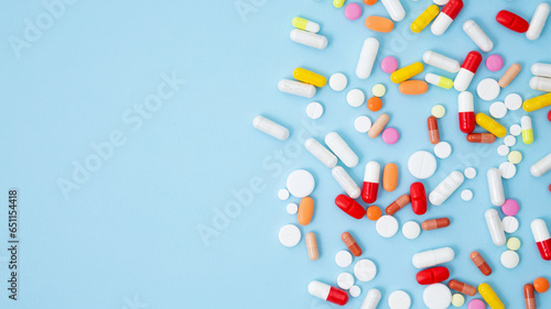 Obraz na plátně Various white medication tablets and capsules on blue background