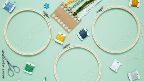 Embroidery set fot stitching on green background with embroidery hoop, fabric, colorful threads, scissors and needls. Indoor hobby concept with copy space, top view photo