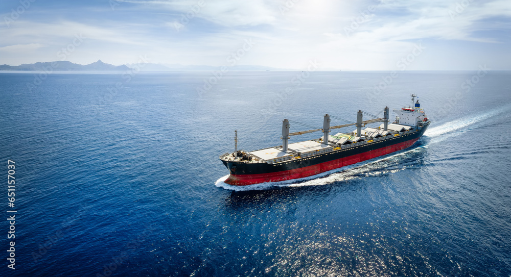 Aerial view of a bulk carrier cargo vessel traveling with high speed over blue sea with copy space as a concept for import and export industry