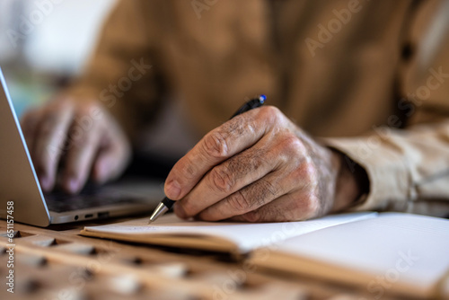Senior man working with financial papers at home. Elderly man working on monthly expenses accounts. Finances, savings, annuity insurance and bills counting taxes