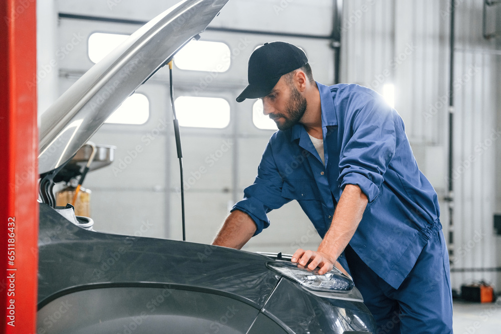 Hood is opened. Auto mechanic working in garage. Repair service Hood is opened. Auto mechanic working in garage. Repair service