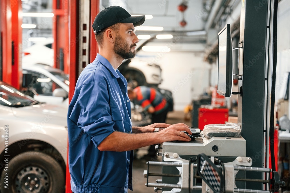 Standing by computer terminal. Auto mechanic working in garage. Repair service Standing by computer terminal. Auto mechanic working in garage. Repair service