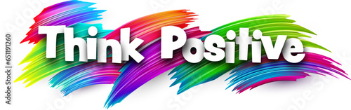 Think positive paper word sign with colorful spectrum paint brush strokes over white.