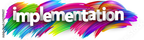Implementation paper word sign with colorful spectrum paint brush strokes over white.