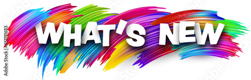 What's new paper word sign with colorful spectrum paint brush strokes over white.