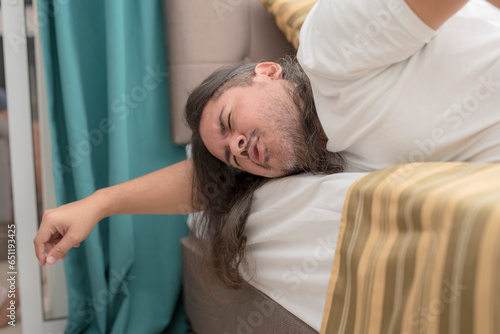 Obraz na plátně A man feeling excruciating stomach pain while lying prone on the edge of the bed