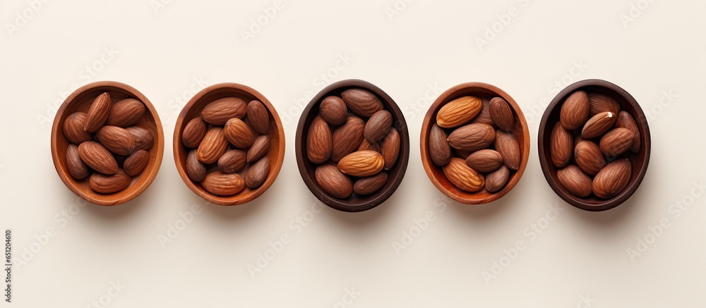 Five sweet brown chocolate cinnamon almonds in small wooden bowl on a isolated pastel background Copy space isolated Five sweet brown chocolate cinnamon almonds in small wooden bowl on a isolated pastel background Copy space isolated