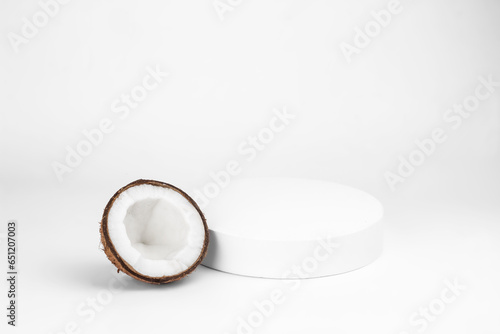 Empty white podium and tropical broken coconut on a white background.