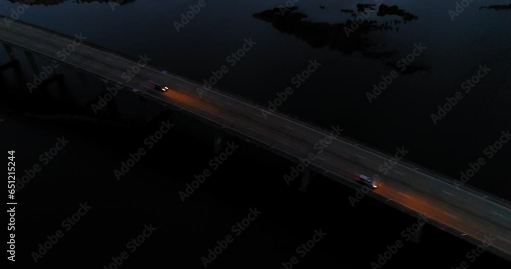 Aerial Backward Tilt Up Shot Of Vehicles On Bridge Over Sea Against Cloudy Orange Sky At Dusk - New Orleans, Louisiana Aerial Backward Tilt Up Shot Of Vehicles On Bridge Over Sea Against Cloudy Orange Sky At Dusk - New Orleans, Louisiana